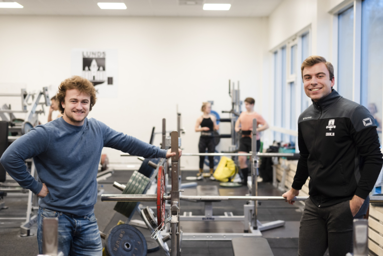Erik Hartman and Simon Söderlund in a weightlifting gym.