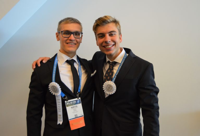 Nikita and Erik Hartman wearing prize rosettes at Intel ISEF.